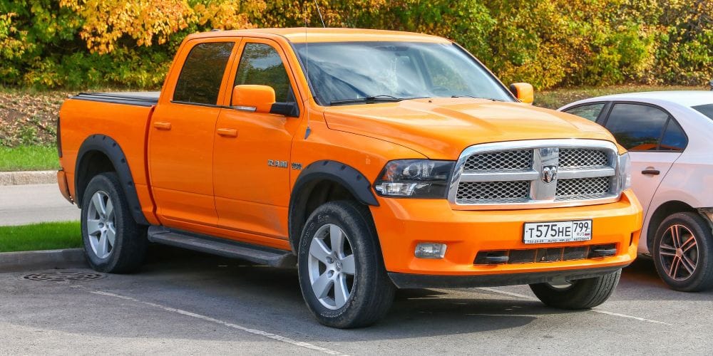 Bright orange Dodge Ram pickup truck parked in an outdoor parking space