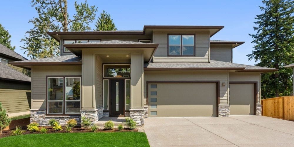 Exterior front view of a modern two-story single-family residential home with a three-car garage and manicured front lawn